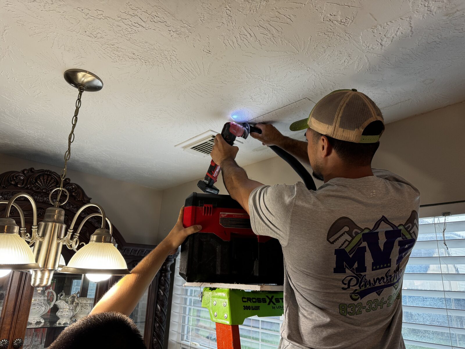 MVP Plumbing technician cutting a ceiling with a dust extractor to reach a leak